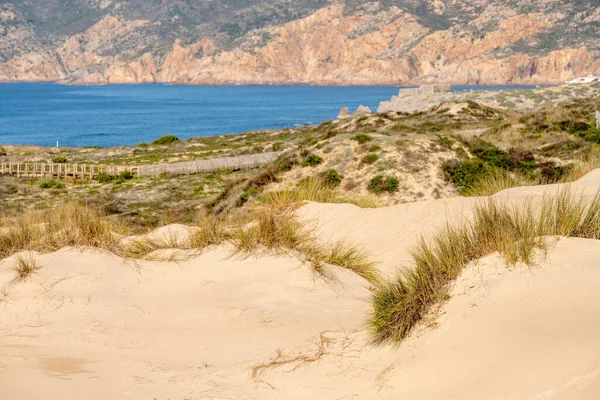 Soft sand dunes shaped by coastal wind with sparse grass above the Atlantic shoreline near Guincho Cascais Portugal.