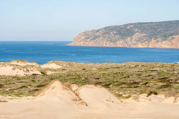 Expansive sand dunes and coastal vegetation with a wide view of the Atlantic Ocean near Guincho Cascais Portugal.
