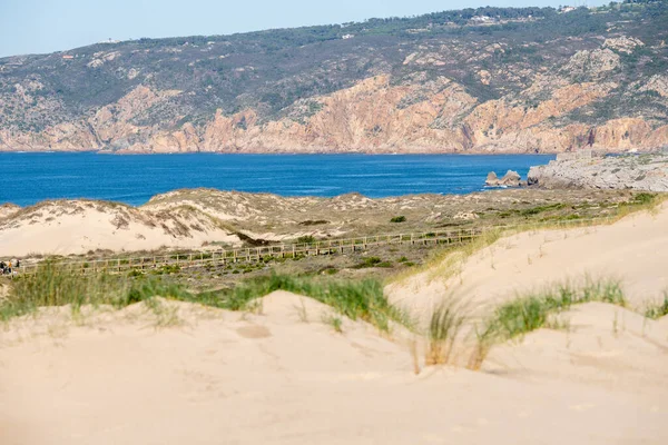 Rolling sand dunes with coastal grass and open Atlantic Ocean views along the Guincho coastline near Cascais Portugal.