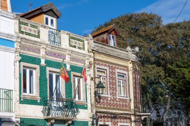 Alcochete Portekiz 19 Aralık 2025. Mavi gökyüzünün altında azulejo fayansları, balkonlar ve Portekiz bayraklarıyla dekore edilmiş geleneksel konut binası..