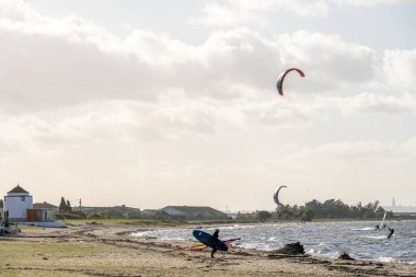 Alcochete Lizbon, 19 Aralık 2025. Uçurtmacı, Tagus nehrinin üzerinde uçan uçurtmalarla dolu kumlu nehir sahilinde yürüyor..
