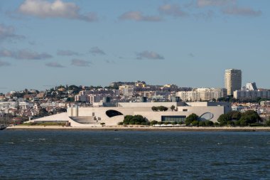 Lizbon Portekiz 24 Aralık 2025. MAAT müzesi açık bir gökyüzünün altında geniş bir Lizbon silueti ile Tagus nehri boyunca uzanır..