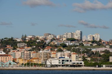 Lizbon Portekiz 24 Aralık 2025. Gündüz vakti Belem ilçesinde iskan binaları ve nehir kenarındaki gezinti yerlerini gösteren liman manzarası var..