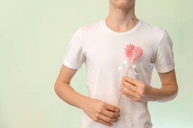 Genç bir adam elinde kalp şeklinde pembe bir lokum tutuyor. Yumuşak odak.