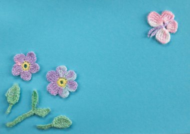 Aquamarine arka planında örülmüş ürünlerin bir kompozisyonu var. Çiçekler ve kelebeklerle bir bahar ya da yaz gününün taklidi.