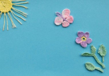 Aquamarine arka planında örülmüş ürünlerin bir kompozisyonu var. Çiçek, kelebek ve güneş ile bir bahar veya yaz gününün taklidi.