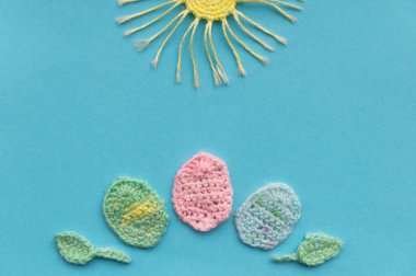 Aquamarine arka planında örülmüş ürünlerin bir kompozisyonu var. Paskalya günü taklidi. Güneş ve yumurta..