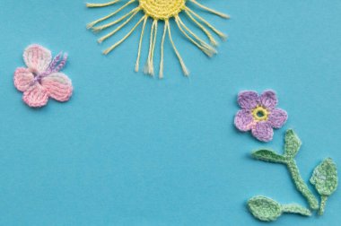 Aquamarine arka planında örülmüş ürünlerin bir kompozisyonu var. Çiçek, kelebek ve güneş ile bir bahar veya yaz gününün taklidi