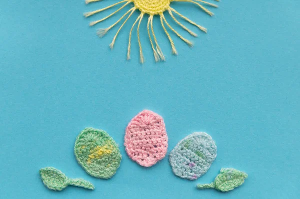 Aquamarine arka planında örülmüş ürünlerin bir kompozisyonu var. Paskalya günü taklidi. Güneş ve yumurta..