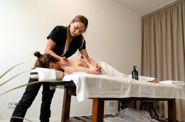 Bir masöz, küçük bir masaj salonundaki müşteriye rahatlatıcı bir masaj yapar. Atmosfer sakin, yoğun bir iş gününde rahatlamak için mükemmel..