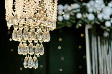 Tavandan süslemelerle dolu bir odada kristalden yapılmış bir avize asılıyor. Beyaz ışıklar ve süsler bir olay sırasında şenlikli bir atmosfer yaratır..