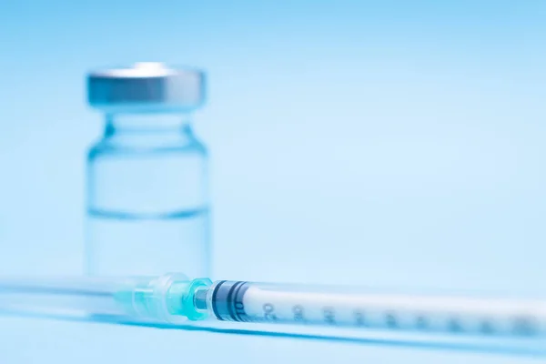 Seringa Lado Uma Garrafa Para Colocar Uma Vacina Fundo Azul — Fotografia de Stock