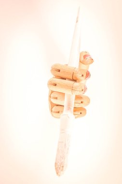 Beyaz arka planda beyaz boya fırçası olan tahta bir el..