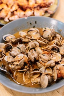 Derin bir tabakta servis edilen sosta pişirilmiş midyeler..