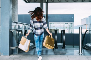 Alışveriş merkezinde çantalı bir kadın yürüyor..