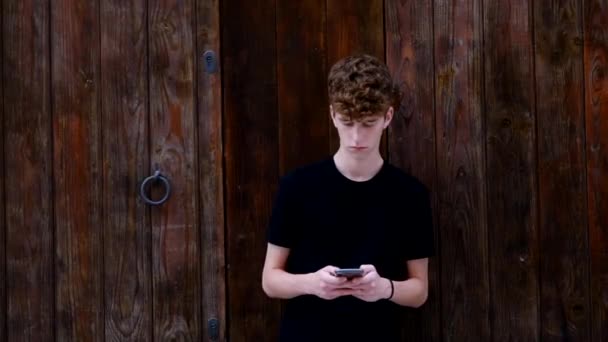 Teenager Guardando Telefono Appoggiato Una Porta Legno — Video Stock