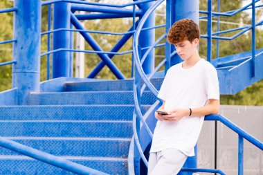 Ergen, birini beklerken telefona bakıyor.