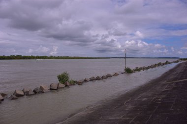 Coxs Bazar yakınlarındaki Bakkhali Nehri 'nin sakin gelgit sularını, balıkçı teknelerini ve uzak mangrovları gösteren huzurlu bir manzarası. Nehir Chittagong Arakan tepelerinden yükselir ve Maheshkhali Kanalı 'na akar..