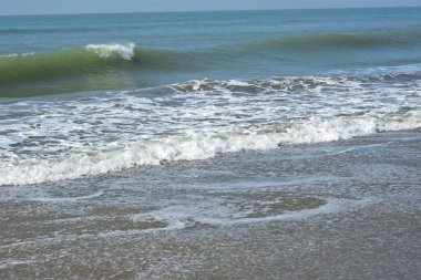 Sakin ve sakin deniz suyu Laboni Sahili 'nin düz kumları üzerinde yavaşça akıyor, parlak gökyüzünü ve Cox' s Bazar sahil şeridinin gezginler ve turistler için huzurlu doğasını yansıtıyor..