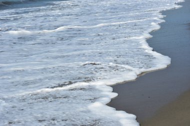 Sakin ve sakin deniz suyu Laboni Sahili 'nin düz kumları üzerinde yavaşça akıyor, parlak gökyüzünü ve Cox' s Bazar sahil şeridinin gezginler ve turistler için huzurlu doğasını yansıtıyor..