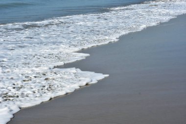 Cox 's Bazar, Bangladeş' teki Laboni Sahili 'nin altın kumlarını kaplayan yumuşak beyaz bir dalganın çıtır çıtır bir yakın çekimi, dünyanın en uzun doğal deniz sahili, parlak sahil gün ışığı altında..