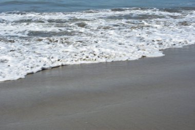 Cox 's Bazar, Bangladeş' teki Laboni Sahili 'nin altın kumlarını kaplayan yumuşak beyaz bir dalganın çıtır çıtır bir yakın çekimi, dünyanın en uzun doğal deniz sahili, parlak sahil gün ışığı altında..