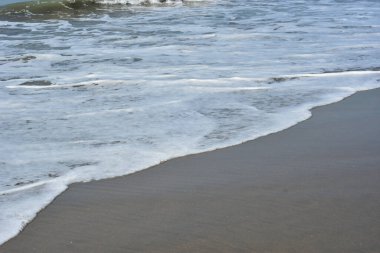 Cox 's Bazar, Bangladeş' teki Laboni Sahili 'nin altın kumlarını kaplayan yumuşak beyaz bir dalganın çıtır çıtır bir yakın çekimi, dünyanın en uzun doğal deniz sahili, parlak sahil gün ışığı altında..