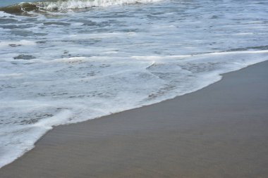 Cox 's Bazar, Bangladeş' teki Laboni Sahili 'nin altın kumlarını kaplayan yumuşak beyaz bir dalganın çıtır çıtır bir yakın çekimi, dünyanın en uzun doğal deniz sahili, parlak sahil gün ışığı altında..