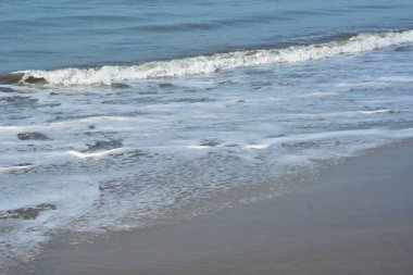 Cox 's Bazar, Bangladeş' teki Laboni Sahili 'nin altın kumlarını kaplayan yumuşak beyaz bir dalganın çıtır çıtır bir yakın çekimi, dünyanın en uzun doğal deniz sahili, parlak sahil gün ışığı altında..