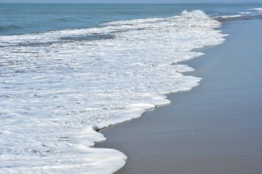 Laboni Sahili 'ndeki altın kumla çarpışan bir dalganın eşsiz çapraz perspektifi, Bangladeş' teki Cox 's Bazar turist merkezinde denizin dinamik enerjisini vurguluyor..