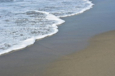 Laboni Sahili 'ndeki altın kumla çarpışan bir dalganın eşsiz çapraz perspektifi, Bangladeş' teki Cox 's Bazar turist merkezinde denizin dinamik enerjisini vurguluyor..