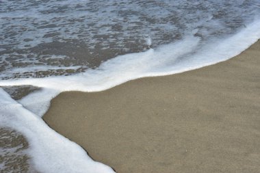Yumuşak deniz köpüğü ve beyaz kabarcıklar, Cox 's Bazar' da popüler bir turizm beldesi olan Laboni Sahili 'nin ıslak kıyılarında parıldıyor. Canlı atmosferi ve çarpıcı Bengal Körfezi manzaralarıyla tanınıyor..