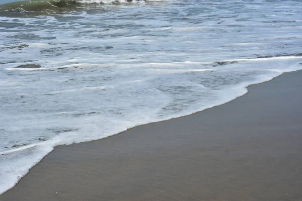 Cox 's Bazar, Bangladeş' teki Laboni Sahili 'nin altın kumlarını kaplayan yumuşak beyaz bir dalganın çıtır çıtır bir yakın çekimi, dünyanın en uzun doğal deniz sahili, parlak sahil gün ışığı altında..