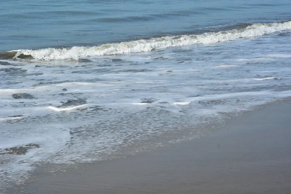 Cox 's Bazar, Bangladeş' teki Laboni Sahili 'nin altın kumlarını kaplayan yumuşak beyaz bir dalganın çıtır çıtır bir yakın çekimi, dünyanın en uzun doğal deniz sahili, parlak sahil gün ışığı altında..