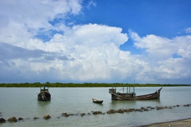Bangladeş 'teki engin bir nehrin geniş açılı görüntüsü dramatik, bulutlu bir gökyüzü altında. Karanlık bulutlar muson mevsiminde sakin su üzerinde güçlü bir atmosfer yaratırlar..