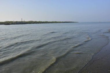 Bakkhali Nehri 'nin sakin bir uzantısı, sığ bir kıyı şeridi boyunca hafif dalgalanmalarla, Bangladeş, Coxs Bazar' da huzurlu bir gelgit nehri manzarasını gösteriyor..