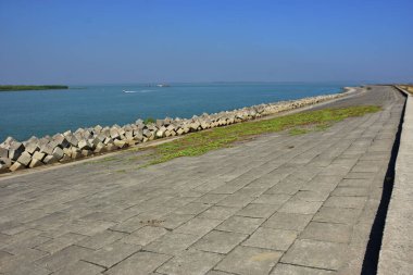 Berrak mavi gökyüzünün altındaki sakin nehir suyu boyunca beton set geçidi. Güçlü perspektif çizgileri olan barışçıl açık hava manzarası, seyahat, altyapı, kentsel planlama, doğa ve çevre kavramları için uygundur..