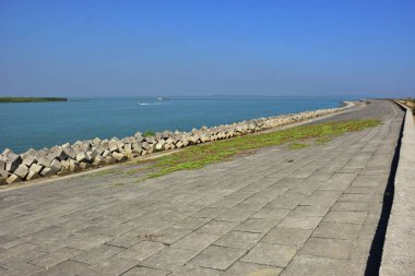 Berrak mavi gökyüzünün altındaki sakin nehir suyu boyunca beton set geçidi. Güçlü perspektif çizgileri olan barışçıl açık hava manzarası, seyahat, altyapı, kentsel planlama, doğa ve çevre kavramları için uygundur..