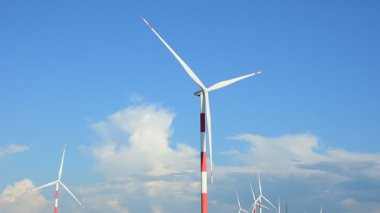 Rüzgar türbini açık mavi gökyüzüne karşı yenilenebilir enerji üretiyor. Temiz enerji kavramı, sürdürülebilir güç, çevre dostu elektrik üretimi, iklim değişikliği çözümü, yeşil teknoloji geçmişi.