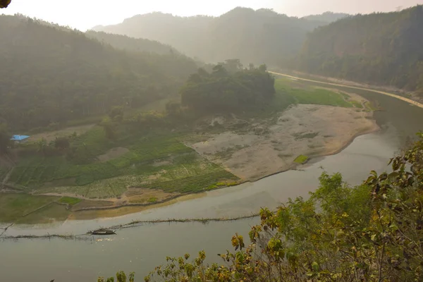 Matamuhuri Nehri 'nin geniş açılı manzarası Lama, Bandarban ve Bangladeş tepelerinden geçiyor. S-eğrisi, kumlu bankalar ve yemyeşil tropikal bitki örtüsü. Sıcak öğleden sonra ışığıyla vadinin üzerinde yumuşak bir sis var. Bangladeş 'in Yeşil Çatı.