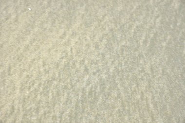 Rüzgâr ve sığ suların oluşturduğu doğal kum dalgalanmaları plaj yüzeyinde soyut desenler oluşturur. Tasarım ve doğa kavramları için ideal minimum kıyı arkaplanı, ince ışık ve organik kumlu detaylar.