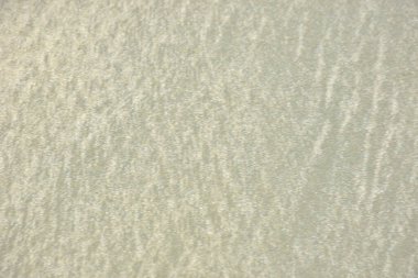 Rüzgâr ve sığ suların oluşturduğu doğal kum dalgalanmaları plaj yüzeyinde soyut desenler oluşturur. Tasarım ve doğa kavramları için ideal minimum kıyı arkaplanı, ince ışık ve organik kumlu detaylar.