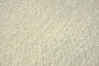 Rüzgâr ve sığ suların oluşturduğu doğal kum dalgalanmaları plaj yüzeyinde soyut desenler oluşturur. Tasarım ve doğa kavramları için ideal minimum kıyı arkaplanı, ince ışık ve organik kumlu detaylar.