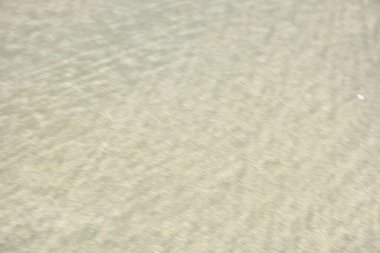 Rüzgâr ve sığ suların oluşturduğu doğal kum dalgalanmaları plaj yüzeyinde soyut desenler oluşturur. Tasarım ve doğa kavramları için ideal minimum kıyı arkaplanı, ince ışık ve organik kumlu detaylar.