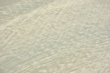 Rüzgâr ve sığ suların oluşturduğu doğal kum dalgalanmaları plaj yüzeyinde soyut desenler oluşturur. Tasarım ve doğa kavramları için ideal minimum kıyı arkaplanı, ince ışık ve organik kumlu detaylar.