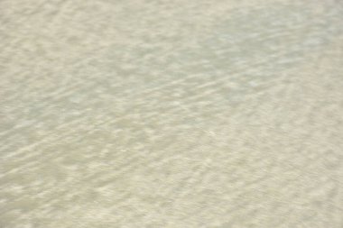 Rüzgâr ve sığ suların oluşturduğu doğal kum dalgalanmaları plaj yüzeyinde soyut desenler oluşturur. Tasarım ve doğa kavramları için ideal minimum kıyı arkaplanı, ince ışık ve organik kumlu detaylar.