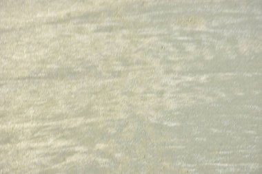 Rüzgâr ve sığ suların oluşturduğu doğal kum dalgalanmaları plaj yüzeyinde soyut desenler oluşturur. Tasarım ve doğa kavramları için ideal minimum kıyı arkaplanı, ince ışık ve organik kumlu detaylar.