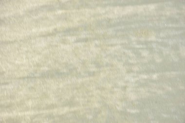 Rüzgâr ve sığ suların oluşturduğu doğal kum dalgalanmaları plaj yüzeyinde soyut desenler oluşturur. Tasarım ve doğa kavramları için ideal minimum kıyı arkaplanı, ince ışık ve organik kumlu detaylar.