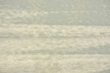 Rüzgâr ve sığ suların oluşturduğu doğal kum dalgalanmaları plaj yüzeyinde soyut desenler oluşturur. Tasarım ve doğa kavramları için ideal minimum kıyı arkaplanı, ince ışık ve organik kumlu detaylar.