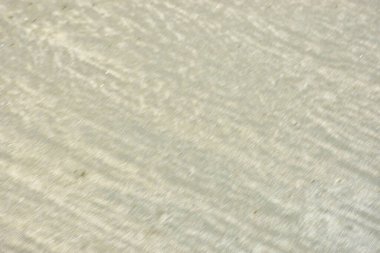 Rüzgâr ve sığ suların oluşturduğu doğal kum dalgalanmaları plaj yüzeyinde soyut desenler oluşturur. Tasarım ve doğa kavramları için ideal minimum kıyı arkaplanı, ince ışık ve organik kumlu detaylar.